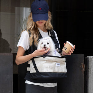 Crossbody dog carrier in vanilla beige keeps a white Maltese close during relaxed coffee runs and city errands.